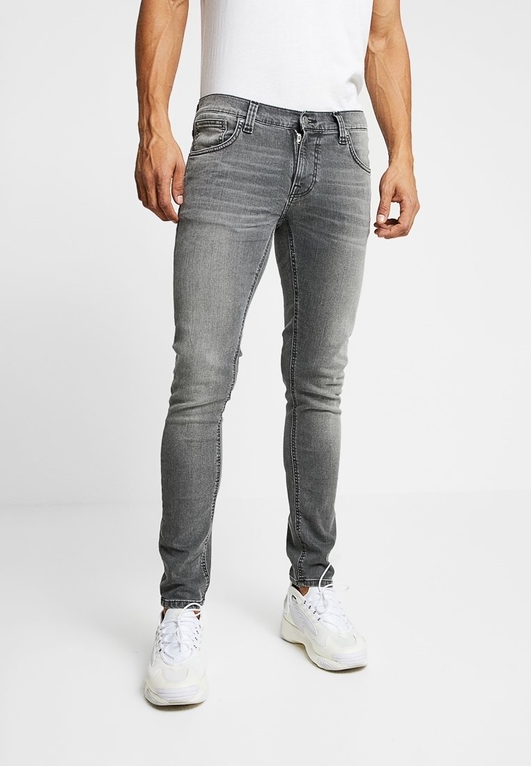 Grå denimjeans med slim fit, framfickor, subtila blekningar och kontrasterande sömmar, parat med vita träningssneakers.