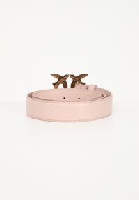 Ceinture en cuir rose pâle roulée avec boucle décorative dorée en forme d’oiseau sur une surface blanche.