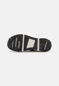Semelle d’une chaussure noire et blanche avec des motifs texturés antidérapants et le logo « Continental » sur la bande de roulement en caoutchouc au centre.