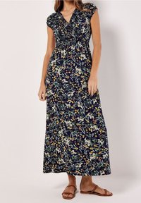 Floral print maxi dress with cap sleeves, navy background, elasticized waist, and various colored flowers. Paired with brown sandals.