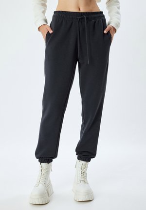 Mørkegrå sweatpants lavet af blødt materiale med elastisk talje, snor og elastiske ankelmanchetter. Lommer på hver side.