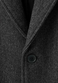 Manteau en tweed gris présentant un motif tissé texturé, des revers crantés et une fermeture à un bouton noir. Matière douce avec une apparence chaude.