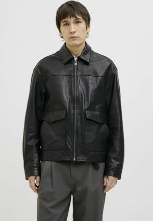 Black leather jacket with a zip front, point collar, two front patch pockets, and a smooth, shiny texture. Casual fit and modern design.