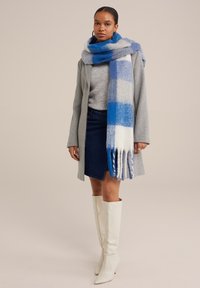 Flerfärgad blå och vit rutad scarf gjord av mjuk ull, kombinerad med en grå kappa, denimkjol och knähöga vita stövlar.