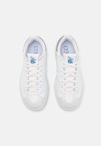 Paire de baskets blanches New Balance CT32 avec lacets, vue de dessus sur un fond blanc uni.