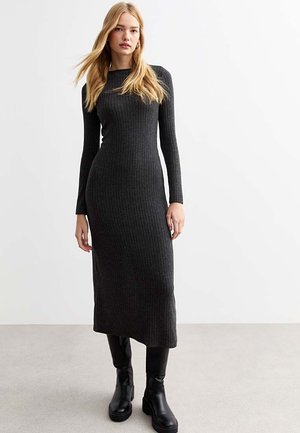 Abito a maniche lunghe in maglia a coste di colore grigio scuro, con una silhouette aderente e scollatura rotonda. Abbinato a stivali neri alla caviglia.