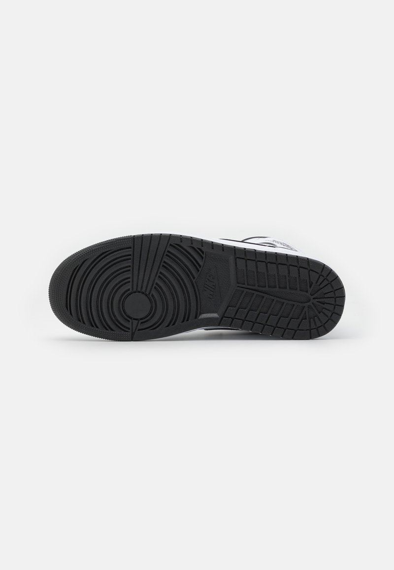 Suela de zapatilla de goma negra con patrones de dibujo circulares y lineales, que presenta un logo en relieve y una textura suave.