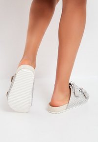Sølv slip-on sko med rhinestone pynt, rund tå, blød beige sål og tekstureret overdel. Velegnet til afslappet brug.