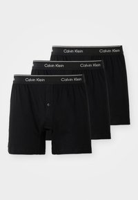 Trei perechi de boxeri negri din bumbac cu gaica, având un elastic negru cu text alb "Calvin Klein".
