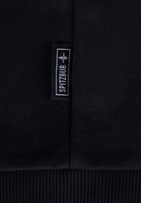 Tessuto a maglia nero con texture a coste, dotato di un'etichetta bianca del marchio "SPITZBUB" cucita sul bordo.