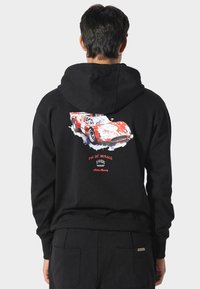 Sudadera negra con un gráfico colorido de un coche de carreras en la parte posterior, con el texto "PAS DE MONACO 1988" y "Arden Racing" debajo del diseño.