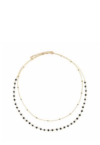 Złota, warstwowa naszyjnik składający się z dwóch łańcuszków z przemiennie rozmieszczonymi czarnymi koralikami i złotymi akcentami, prezentujący delikatny i minimalistyczny design.
