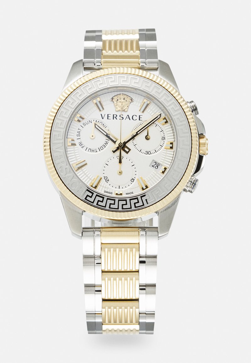 Montre Versace avec un bracelet en métal argenté et doré, cadran blanc, motif clé grec noir et sous-cadrans de chronographe. Comprend le logo du lion.