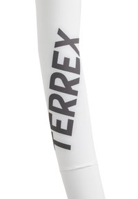 Valkoinen urheiluhiha, jossa on vahva musta teksti "TERREX". Sujuva, joustava materiaali ja tiukka muotoilu.