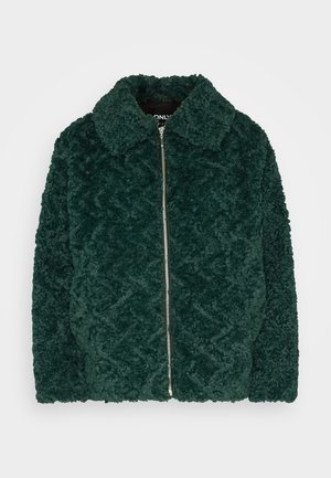 Sötétzöld, plüss fleece dzseki gyémánt mintával, cipzáras záródással és hegyes gallérral. Puha tapintású és nagy elülső felülettel rendelkezik.