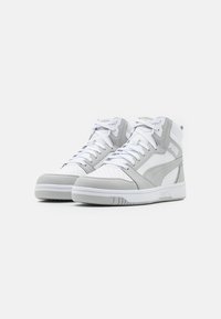 Baskets montantes en cuir gris et blanc avec un bout perforé, des lacets plats, un col rembourré et un logo proéminent sur le côté.