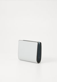 Kompakte Geldbörse aus hellblauem strukturiertem Leder mit gefaltetem Design. Verfügt über zwei Fächer mit dunkelblauem Innenraum und glatten Kanten.
