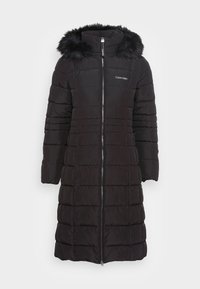 Cappotto puffo nero con zip frontale, colletto alto e cappuccio con bordo in pelliccia. Presenta una texture trapuntata e un logo ricamato sul petto.