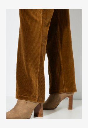 Brown corduroy wide-leg pants with vertical ribbed texture, paired with beige ankle boots featuring a square block heel.