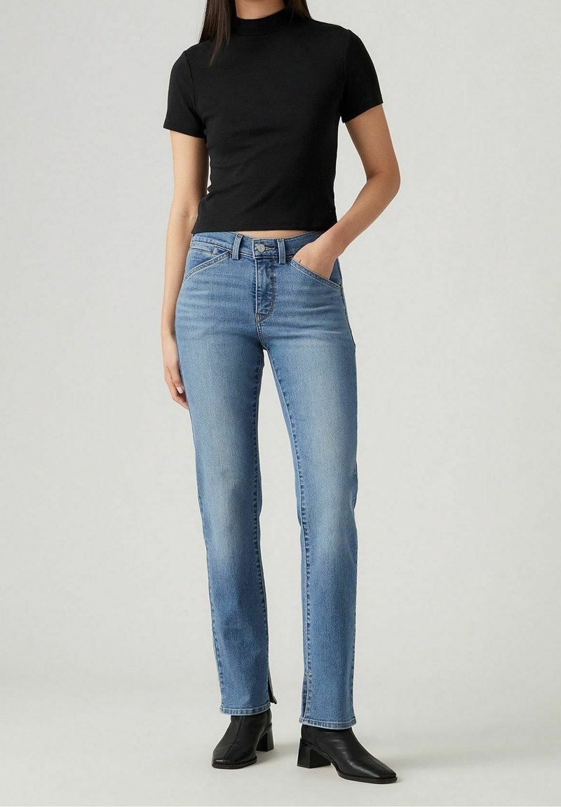 Camiseta negra corta combinada con jeans de denim azul claro. Los jeans tienen un corte recto, diseño de cinco bolsillos y un ligero desgaste en los dobladillos.