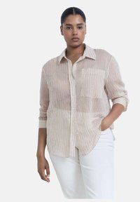 Camicia leggera a righe beige con sottili righe rosse e blu, con bottoni davanti e taschino sulla parte sinistra del petto; maniche arrotolate fino ai gomiti.
