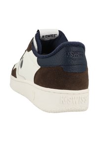 K-Swiss shoes with white leather and brown suede upper, navy accents, textured heel, and logo on the back. Flat rubber sole with grip pattern.