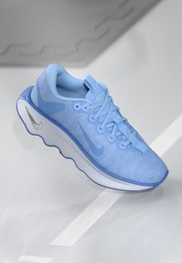 Svetlo modra Nike superga z teksturirano mrežasto zgornjo plastjo, okroglo podplatnico in srebrno logotipno akcentacijo na strani. Ravne vezalke in oblazinjen ovratnik.