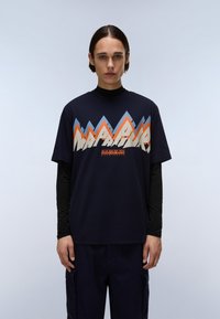 Tricou bleu marin cu un grafic îndrăzneț de munte în portocaliu, albastru deschis și crem. Mâneci scurte peste un strat de bază negru cu mânecă lungă.