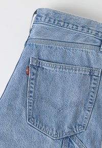 Φωτεινό γαλάζιο τζιν τζινάκι διπλωμένο για να φαίνεται η πίσω τσέπη με ορατή ραφή και μια μικρή κόκκινη ετικέτα της μάρκας Levi's.