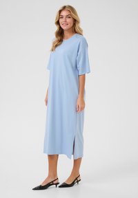Svetlomodré midi šaty s krátkymi, širokými rukávmi a bočnými štrbinami. Hladká tkanina s voľným strihom a okrúhlym výstrihom. Čierne slingback podpätky.