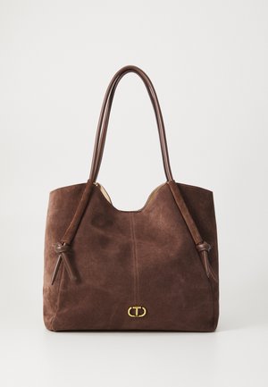 Sac cabas en daim marron avec des poignées en cuir lisse, un haut arrondi et un détail de logo doré accentué à l'avant.