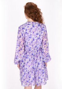 Lila Blumenkleid mit langen Ärmeln, gerafftem Taillenbereich und gestuftem Saum. Hergestellt aus leichtem, transparentem Stoff mit sanften Lavendel- und Pfirsichmustern.