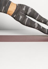 Legginsy w kamuflażowy wzór w odcieniach szarości i czerni, wykonane z elastycznego materiału; wysoki stan, dopasowany krój i gładka tekstura.