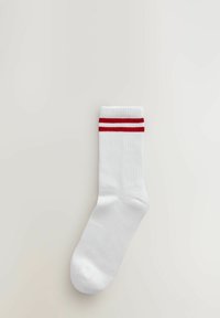 Witte katoenen sok met ribbelstructuur, met aan de bovenkant twee rode horizontale strepen. Gladde teen en enkellange stijl.