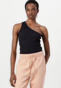 Black ribbed one-shoulder top paired with light pink drawstring pants, featuring an elastic waistband and soft fabric texture.