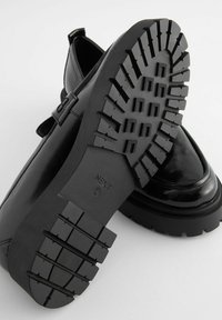 Zwarte gepatineerde leren schoenen met een stevige rubberen zool met een getextureerd loopvlak. Ontworpen met een slanke, afgeronde silhoutte.