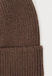 Gorro de punto marrón con una textura acanalada gruesa, que presenta un dobladillo para mayor calidez y un material suave y grueso.