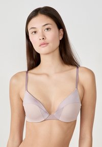Soutien-gorge triangle rose clair avec des bretelles fines et ajustables, fabriqué en satin lisse. Doté d'une couture courbée au centre et de bonnets sans coutures.