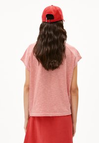 Red and white striped short-sleeve top, soft fabric, relaxed fit, paired with a matching red skirt, worn with a red cap.