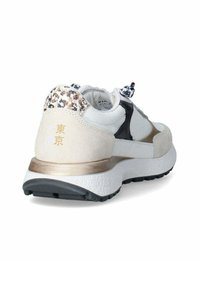Sneaker beige e nera con suola bianca texturizzata, dettagli in oro e tacco con stampa leopardata. Presenta un colletto imbottito e chiusura con lacci.