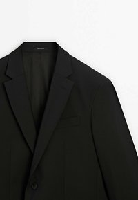 Zwarte blazer met een reverskraag, enkele knoopsluiting en een borstzak. Gemaakt van gladde stof met een subtiele textuur.