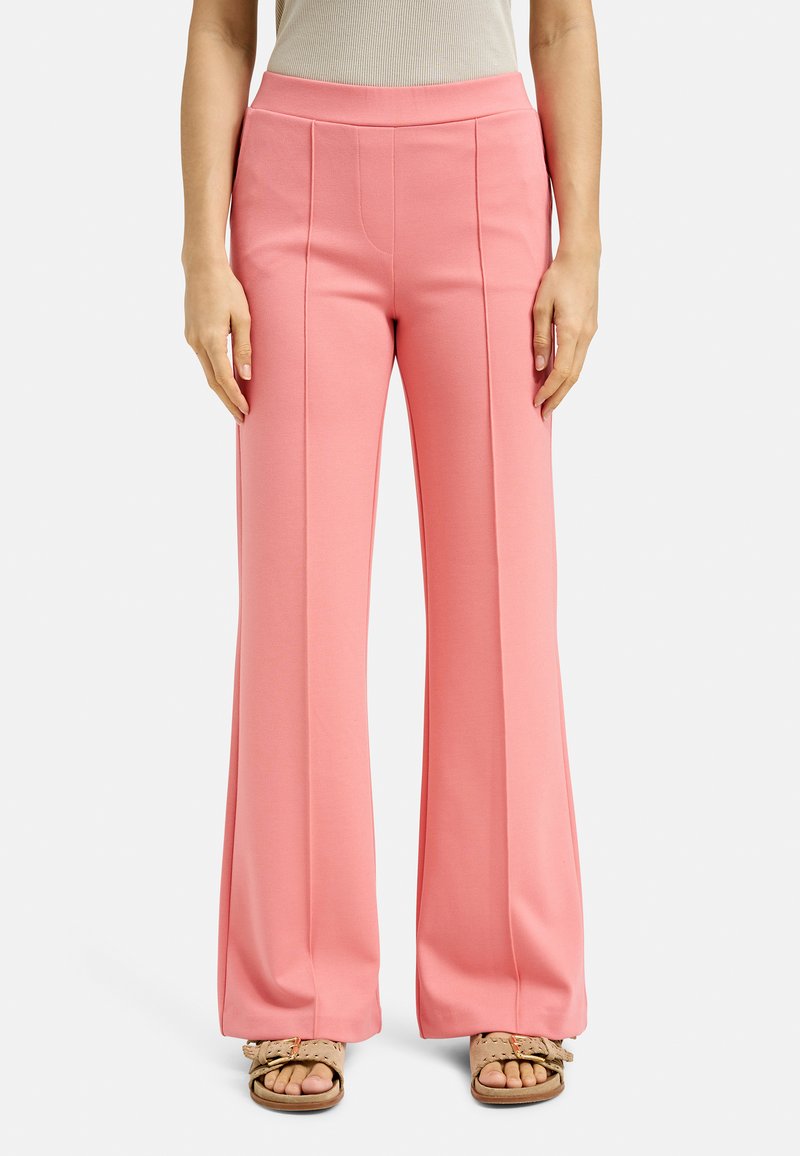 Pale pink wide-leg pants with a smooth texture, featuring front pleats and a high waistband. Worn with light sandals.
