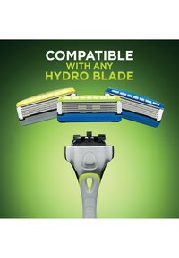 Manche de rasoir avec trois cartouches Hydro Blade interchangeables en jaune, vert et bleu, sur un fond vert avec un texte indiquant la compatibilité.