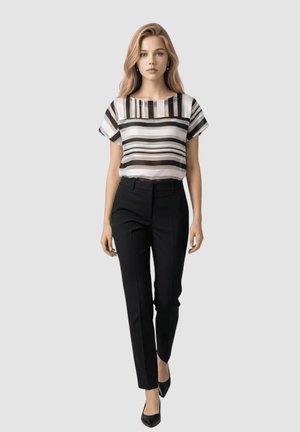 Mujer con cabello largo y rubio, vistiendo una blusa a rayas blancas y negras, pantalones ajustados negros y zapatos negros de punta, caminando hacia adelante.