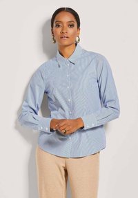 Light blue button-up shirt with thin white stripes, classic collar, long sleeves, and buttoned cuffs. Smooth cotton fabric with maintained shape.