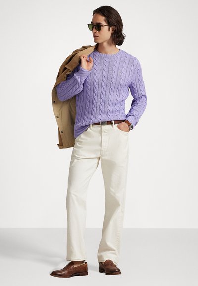 Λεβάντα πουλόβερ με πλεκτό σχέδιο και στρογγυλή λαιμόκοψη, κρεμ παντελόνι, καφέ δερμάτινα παπούτσια και γυαλιά ηλίου, με ένα καφέ παλτό ριγμένο στον έναν ώμο.