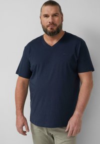 Navyblaues V-Ausschnitt-T-Shirt aus Baumwolle; kurze Ärmel; dezentes Branding auf der Brust; lockere Passform, glatte Textur.