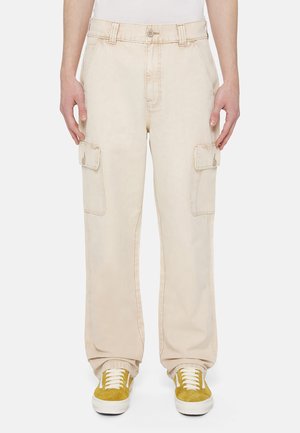 Pantaloni cargo beige con tasche anteriori e laterali, vita strutturata e una vestibilità rilassata. Abbinati a scarpe da ginnastica gialle per un contrasto.