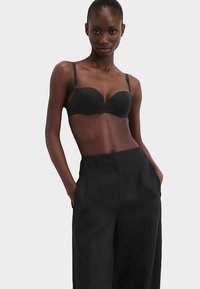 Black underwire bra with smooth cups and adjustable straps, paired with high-waisted wide-leg black trousers. Plain design, no patterns.