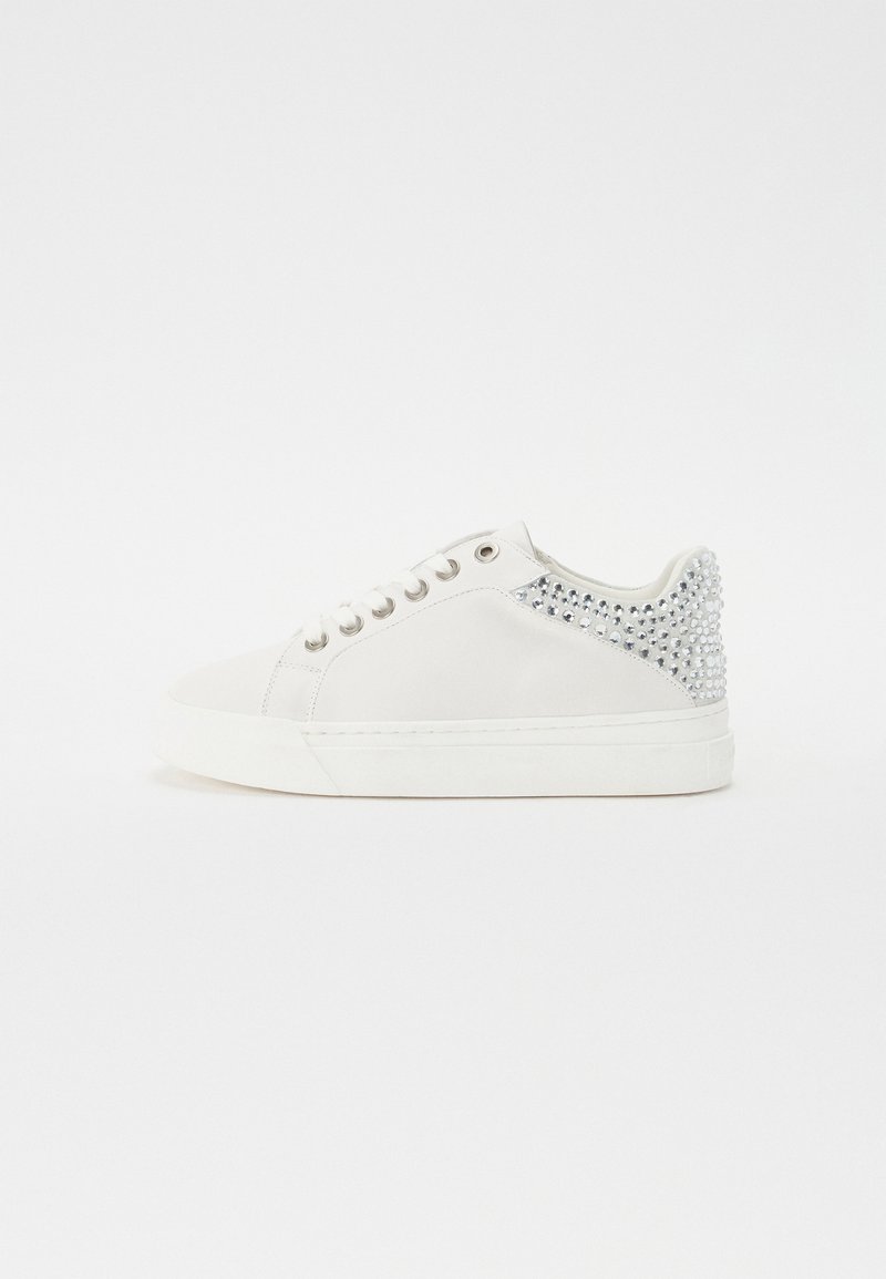 Baltās sporta kedas ar gludu ādas virsu, sudraba rhinestone akcenti uz papēža, apaļš purngals un plakana gumijas zole.